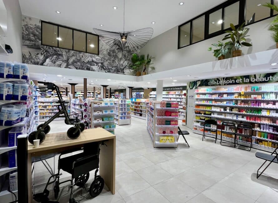 Intérieur de la pharmacie du Marché dans les Bouches-Du-Rhône reagencée par Jean Rolland Agencement. Pharmacie en vue d'ensemble, avec des plantes sur les parois supérieures et des produits de pharmacie et parapharmacie divers.